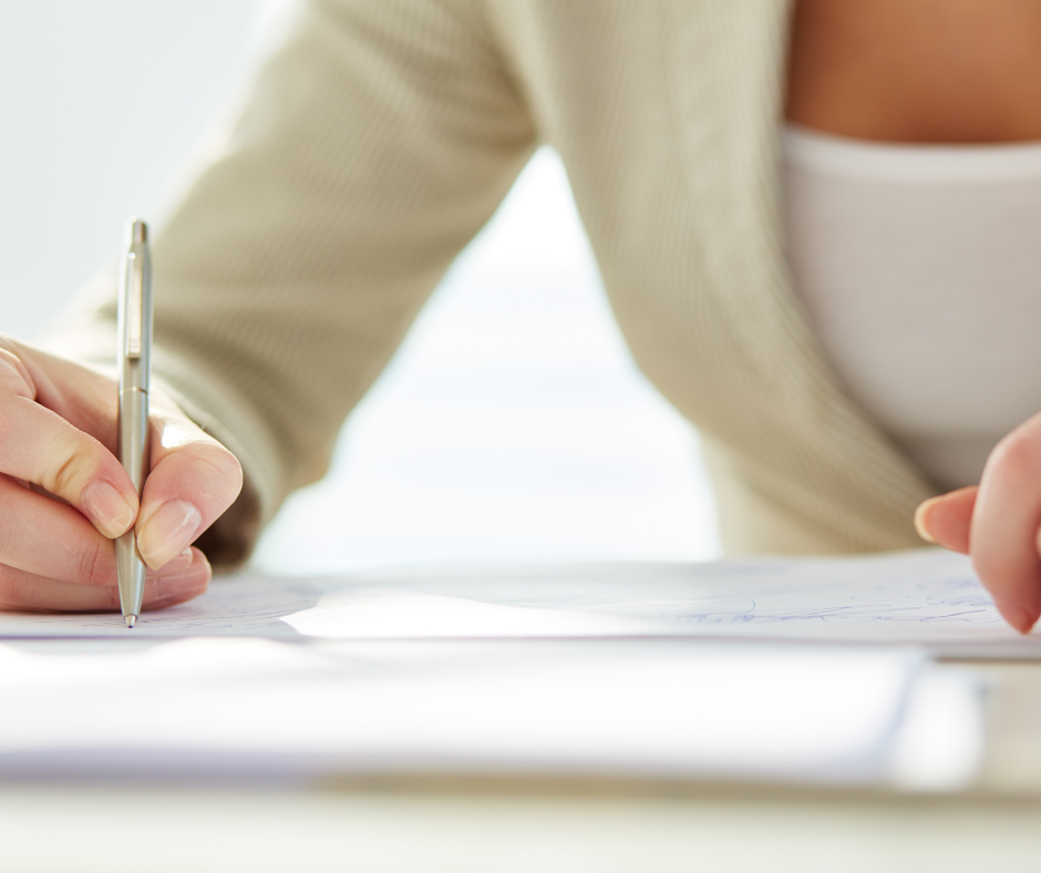 A person sitting down to sign a letter