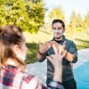 Two people standing outside communicating through sign language with a clear mask on the face